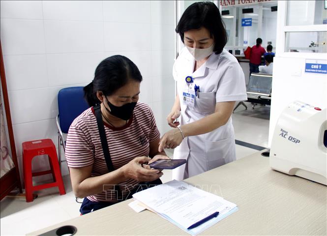 Bác sĩ hướng dẫn người bệnh tra cứu kết quả khám bệnh bằng quét QR Code trên điện thoại di động. (Ảnh: Đồng Thúy/TTXVN)